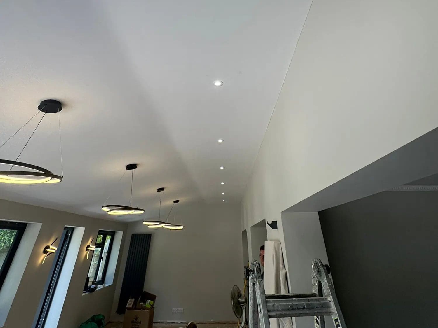 Vaulted extension ceiling with downlights set out in one line and ring pendants below
