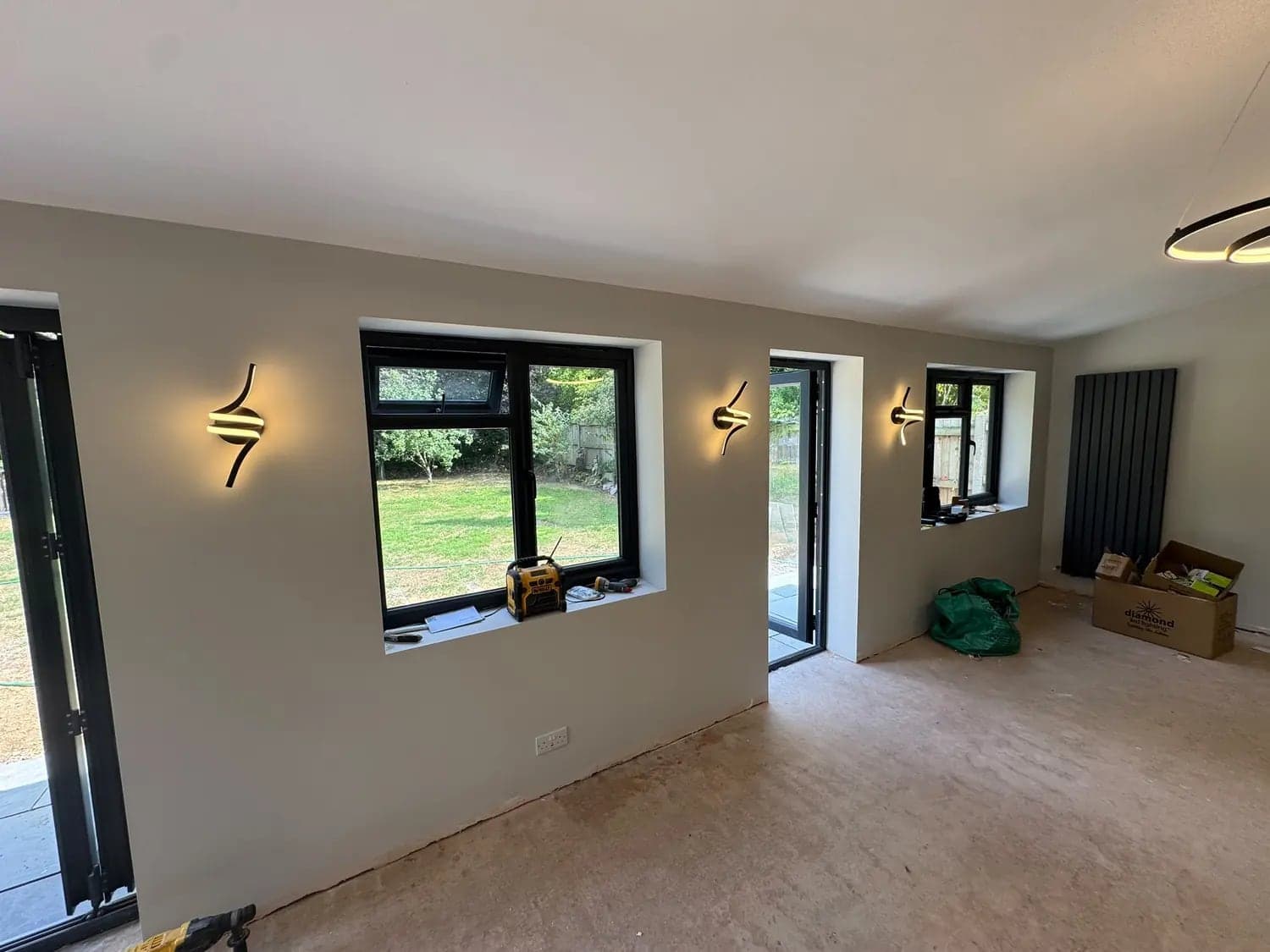 Curved LED wall lights spaced between the windows of a new extension